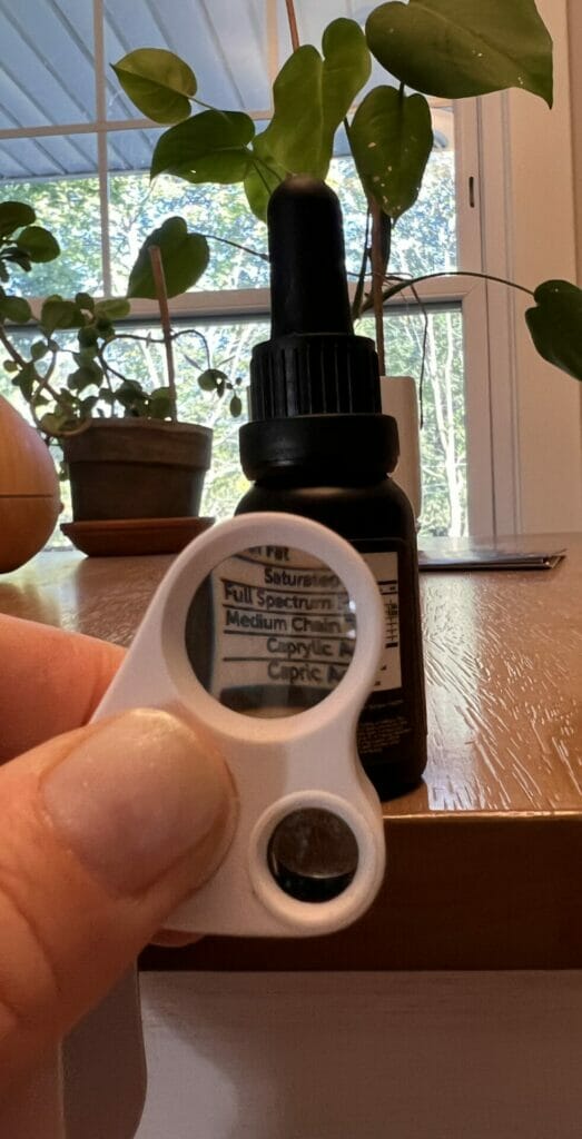 CBD oil bottle magnified by jewelers loupe